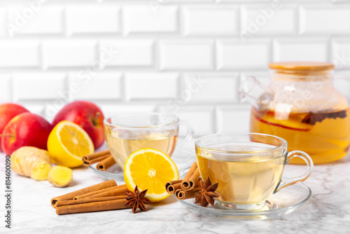 Fragrant hot tea with cinnamon stick and anise on a textured wooden background. A cup of hot tea with honey, lemon, mint and apples. Spicy tea with spices. Immunity tea. Health concept.Copy space.