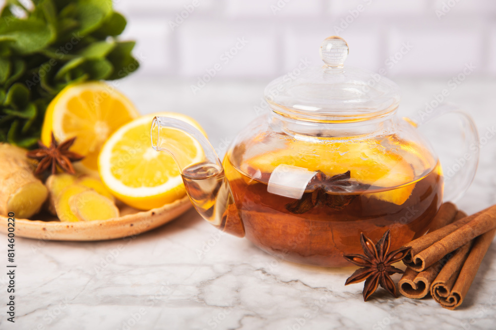 Fragrant hot tea with cinnamon stick and anise on a textured wooden background. A teapot brewing hot tea with honey, lemon, mint and apples. Spicy tea with spices. Immunity tea. Health concept. Fragrant hot tea with cinnamon stick and anise on a textured wooden background. A teapot brewing hot tea with honey, lemon, mint and apples. Spicy tea with spices. Immunity tea. Health concept.