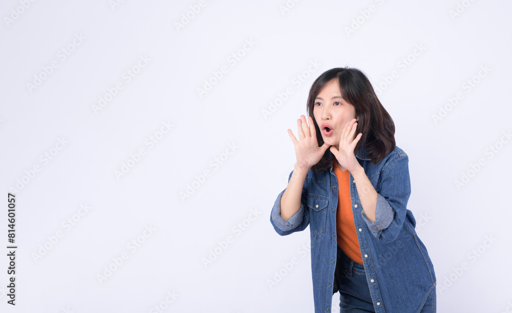 Asian woman wearing orange t shirt and denim jean is posing with a shouting gesture against a white background. Asian woman wearing orange t shirt and denim jean is posing with a shouting gesture against a white background.