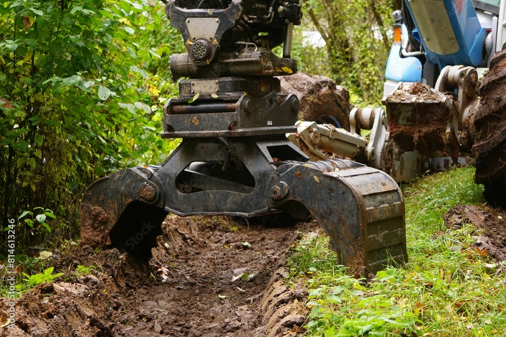 a machine is lifting up some dirt while another one watches a machine is lifting up some dirt while another one watches