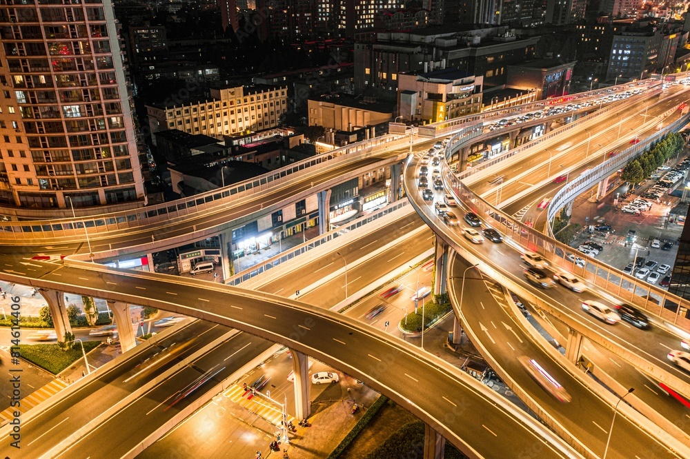 Obraz premium Aerial view of a city illuminated by the headlights of cars driving through an intersection at night