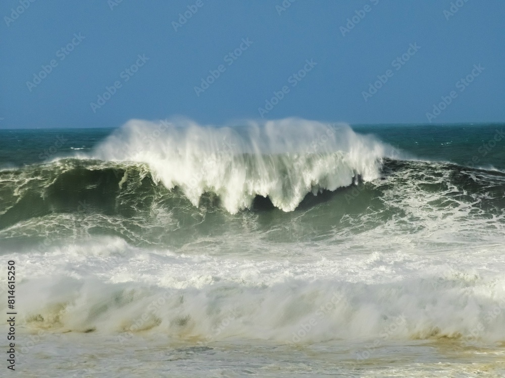 Fototapeta premium waves in the ocean with people standing near it and in the water