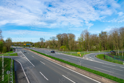 Top view of the highway with rarely passing cars. Blue sky with light clouds.