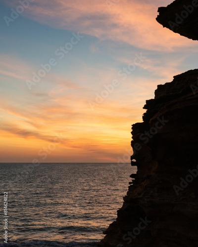 a man standing on top of a academics cliff in the ocean photo