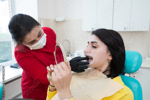 A dentist demonstrates a patient's perfect smile after implanting dental veneers or teeth whitening.