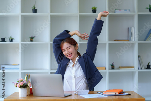 Asian businesswomen feel tired from hard work, thus doing arm stretching to relax the body. Tired Asia woman stretching her hands while working in an office.