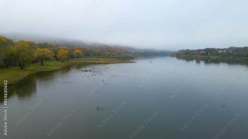 Drone shot of the woods covered with fog on the river bank and riverfront houses on the other bank Drone shot of the woods covered with fog on the river bank and riverfront houses on the other bank