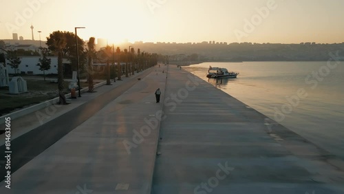 Drone footage over a walkway by a river with shiny sunset scene sky in Istanbul, Turkey photo