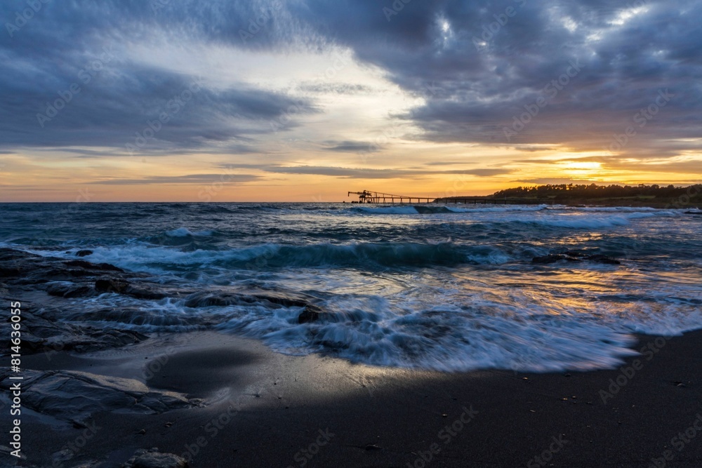 Obraz premium Dramatic seascape at sunset with a pier in the background