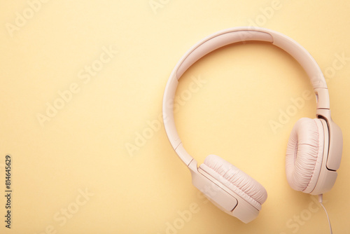 Pink modern headphones on a beige background. Space for text