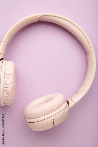 Pink headphones on purple background. Vertical photo