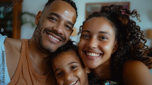 A man  woman  and child are smiling at the camera in a family portrait picture. The Brazilian family trio looks happy and united as they pose for the photo.