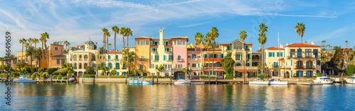 A vast body of water is encircled by numerous palm trees, creating a tropical and scenic landscape. The palm trees add to the beauty of the waters expanse under the bright sky.