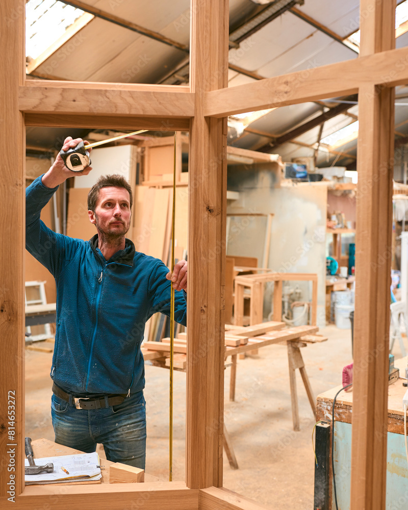 Carpenter In Workshop Measuring Wooden Window Frame Carpenter In Workshop Measuring Wooden Window Frame
