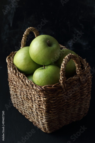 Green apples in a basket on a black background