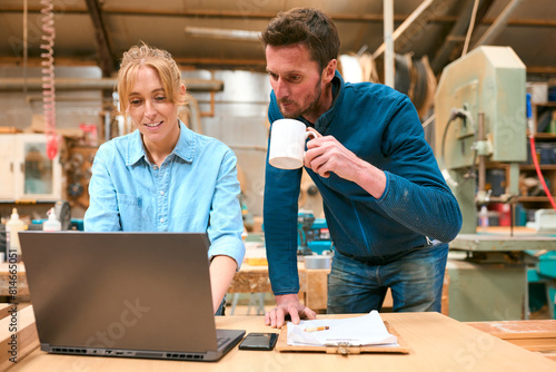 Male And Female Carpenters Working In Woodwork Workshop Using Laptop Together © Monkey Business