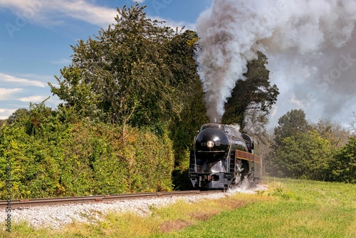 фотографія Rustic steam engine train chugging along a country track, surrounded by lush green fields