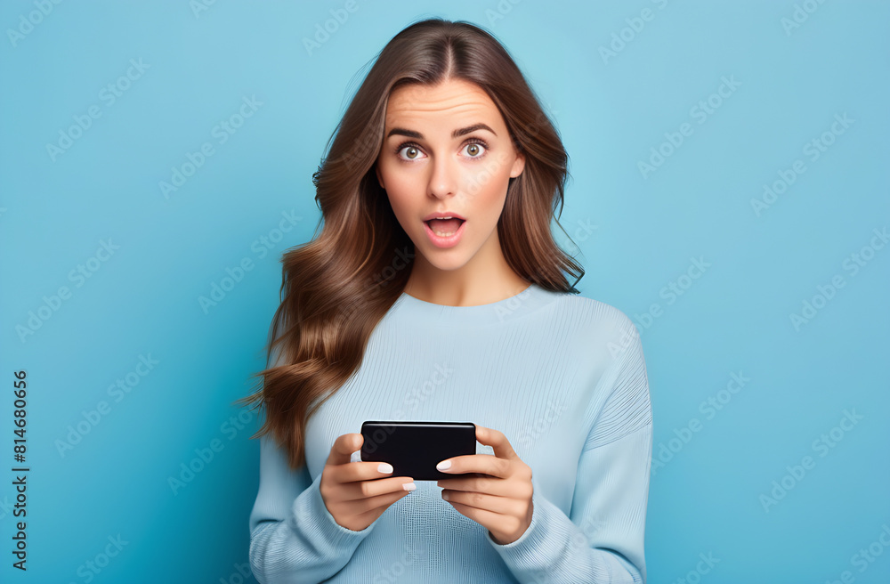 Portrait of a surprised girl with a smartphone in her hands with a curious expression on a blue pastel background Portrait of a surprised girl with a smartphone in her hands with a curious expression on a blue pastel background