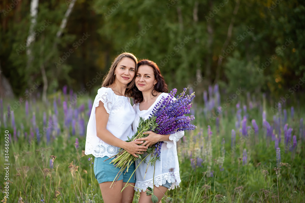 Two beautiful young sisters in a field of lupine flowers. Two beautiful young sisters in a field of lupine flowers.