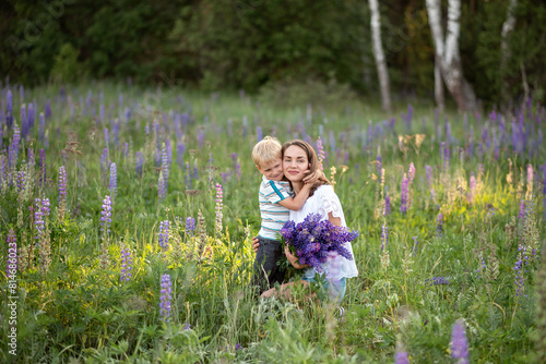 Mother and son in a field with lupine flowers. Summer family concept.