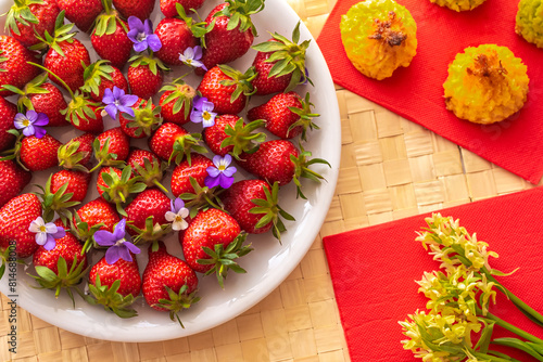 Plate with strawberries, forest spring flowers and cookies.