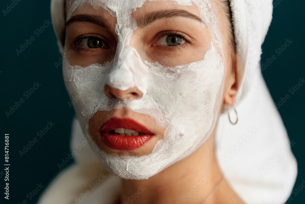 Portrait of a beautiful girl in the studio in a bathrobe and with cream on her face. Grain effect used Portrait of a beautiful girl in the studio in a bathrobe and with cream on her face. Grain effect used