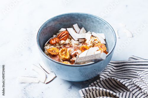 Overnight oatmeal with chocolate, pecans, coconut chips and dried banana, white background.