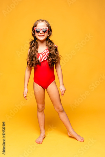 A beautiful cute little girl in a red swimsuit laughs cheerfully on yellow background. Mock up. Summer vacation concept. Advertising of children's products and sale © Irina Mikhailichenko