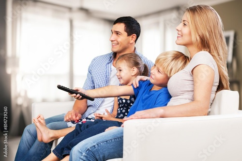 Happy family with children watching TV together at home.