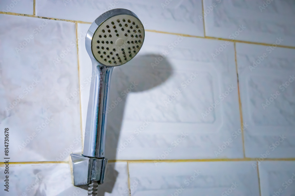 Fototapeta premium Selective focus of old steel shower faucet at white vintage tile background. 