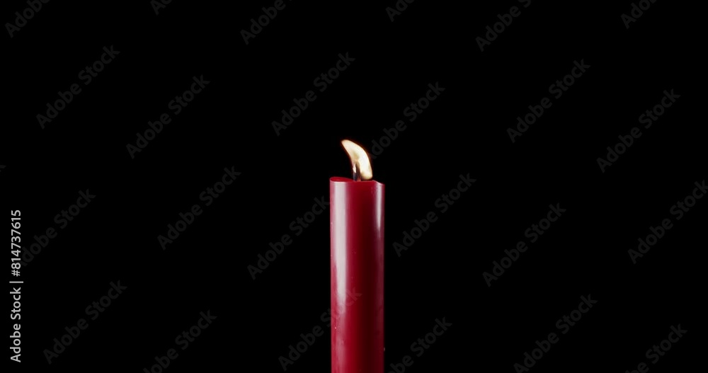 A single red candle burning. Isolated candle burning with dark background. Red paraffin candle with yellow shades burns on a black background. Background or illustration of remembrance or celebration. A single red candle burning. Isolated candle burning with dark background. Red paraffin candle with yellow shades burns on a black background. Background or illustration of remembrance or celebration.