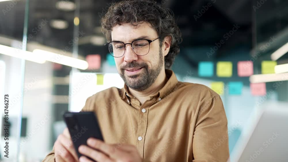 Businessman is using phone while sitting at workplace in business office. Man worker works on mobile application, typing message, chatting with client, banking, ordering or browsing online. Close up Businessman is using phone while sitting at workplace in business office. Man worker works on mobile application, typing message, chatting with client, banking, ordering or browsing online. Close up