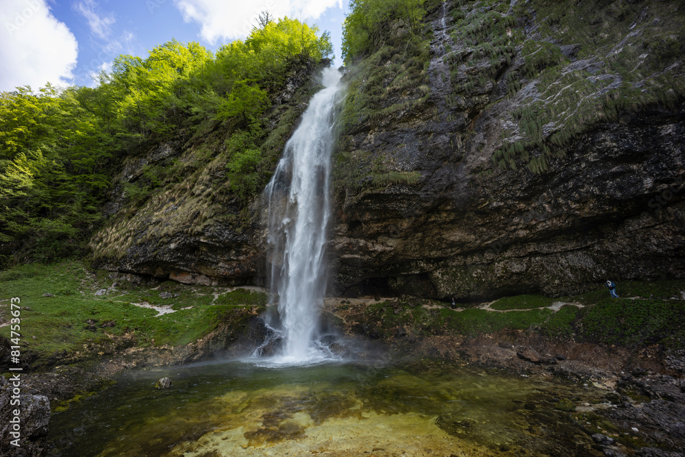 Obraz premium Fontanon of Goriuda, Udine. Wonderful waterfall that falls from a cliff. The force of the waterfall is a sight to behold. Hiking, trekking in the open area surrounded by woods. Summer holidays, peace.