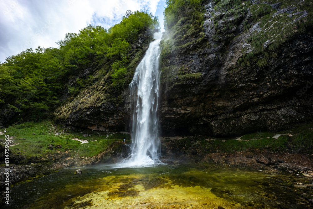 Fontanon of Goriuda, Udine. Wonderful waterfall that falls from a cliff. The force of the waterfall is a sight to behold. Hiking, trekking in the open area surrounded by woods. Summer holidays, peace. Fontanon of Goriuda, Udine. Wonderful waterfall that falls from a cliff. The force of the waterfall is a sight to behold. Hiking, trekking in the open area surrounded by woods. Summer holidays, peace.