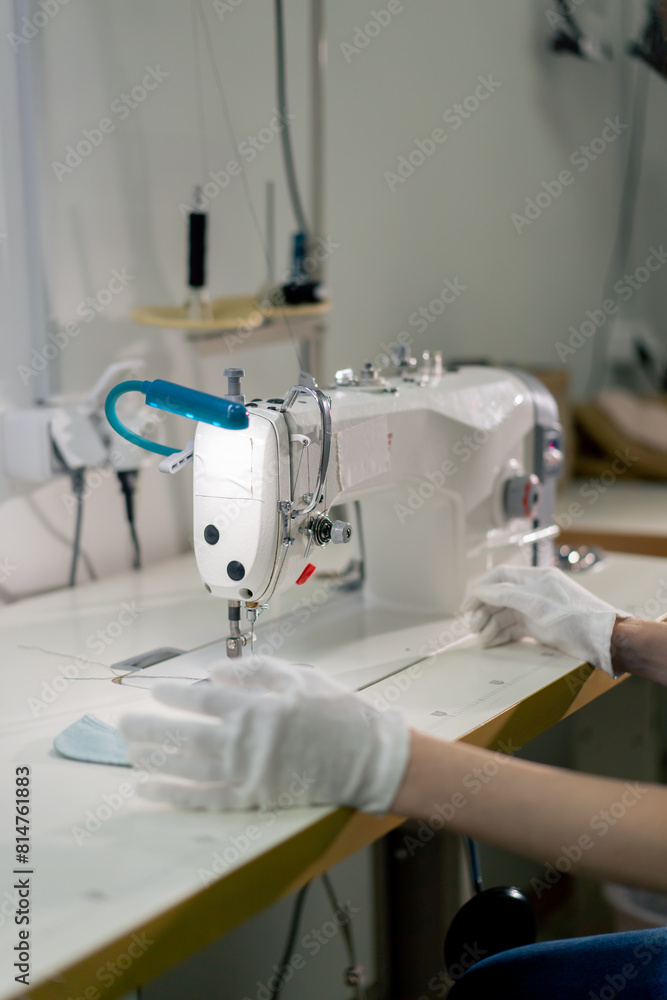 professional dry cleaner young girl hems a patch on a sweater with a sewing machine