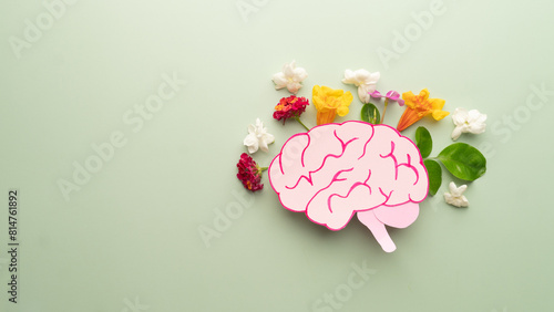 Flat layout of human brain anatomy with colorful fresh flower on green background. Mental health care, positive thinking and creative idea concept.