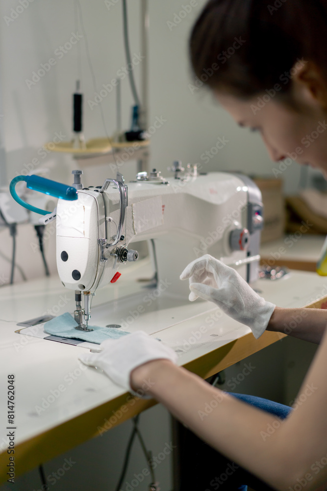 professional dry cleaner young girl hems a patch on a sweater with a sewing machine
