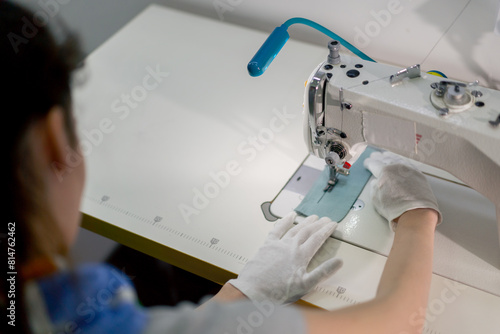 top shot professional dry cleaner young girl hems a patch on a sweater with a sewing machine