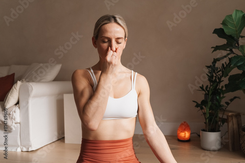 Quadro su tela Young caucasian blond woman practicing alternate nostril breathing pranayama exercise at home