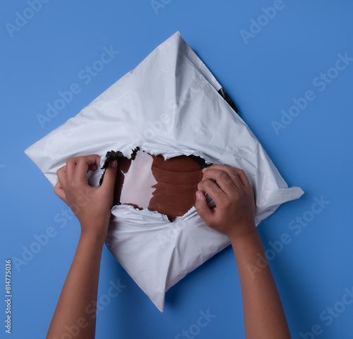 Women hands tear polythene envelope on blue background