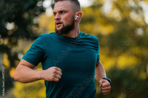 Sporty man running or jogging at the park listening to music on wireless headphones active healthy lifestyle.