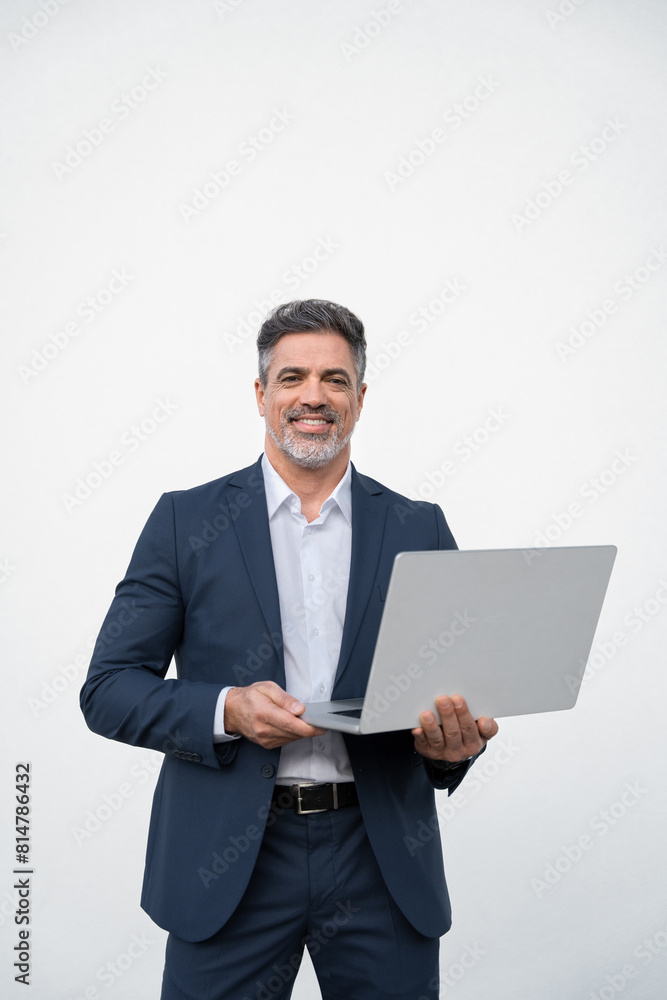 Vertical portrait of middle age mature businessman using pc laptop for business work. Smiling handsome older man in formal suit holding desktop computer, looking at camera. Isolated white background Vertical portrait of middle age mature businessman using pc laptop for business work. Smiling handsome older man in formal suit holding desktop computer, looking at camera. Isolated white background