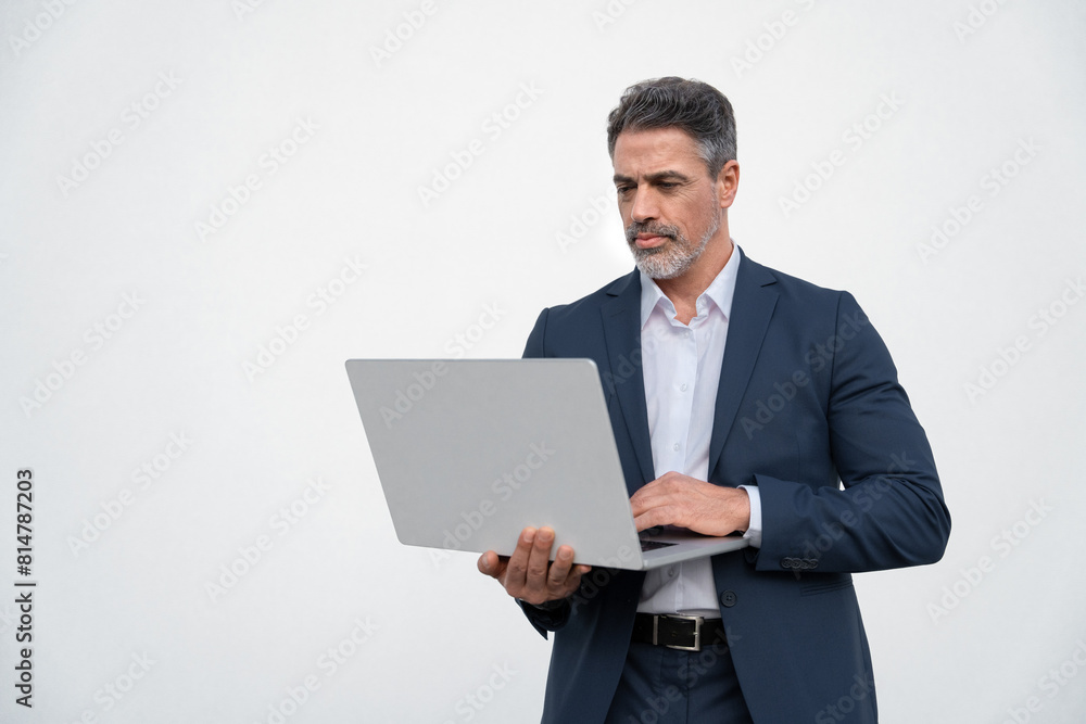 Serious handsome latin older man in formal suit holding desktop computer. Portrait of focused middle age mature businessman using pc laptop for business work. Isolated white background, copy space Serious handsome latin older man in formal suit holding desktop computer. Portrait of focused middle age mature businessman using pc laptop for business work. Isolated white background, copy space