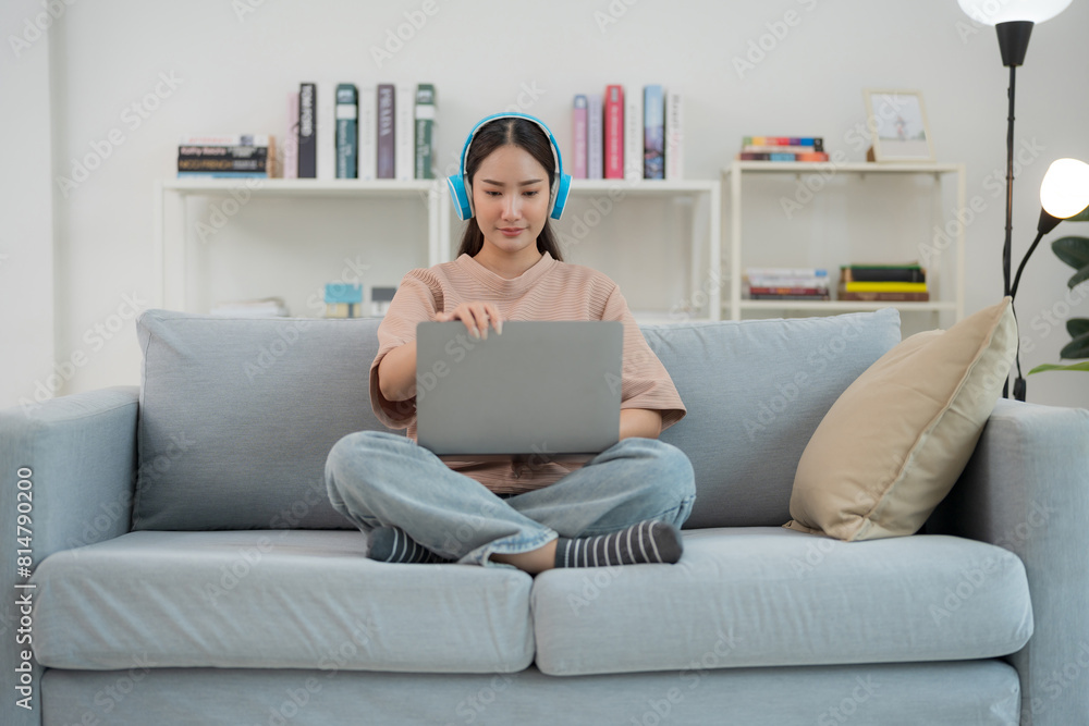 Young woman enjoying music while working on laptop at home Young woman enjoying music while working on laptop at home