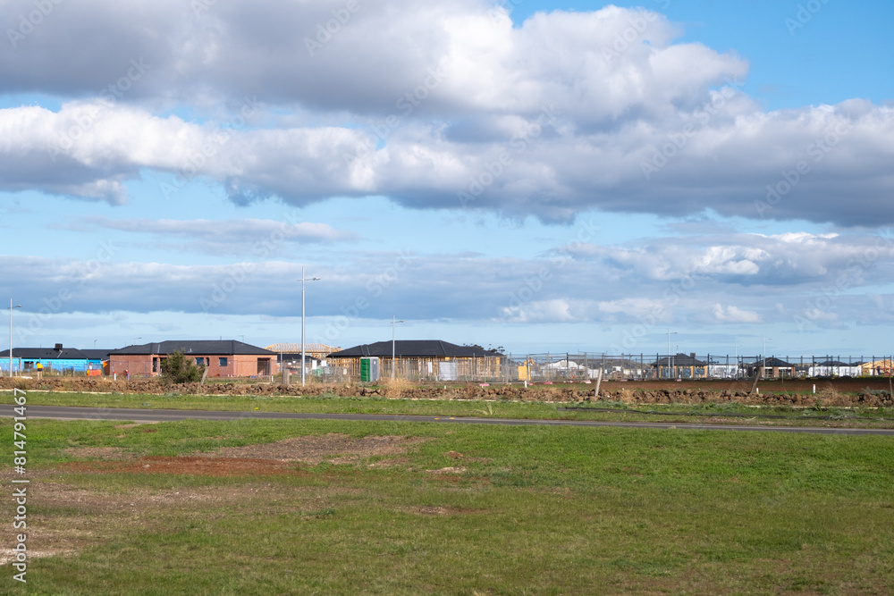 Obraz premium Distance view of a new developed housing estate with large vacant lot of land and many construction sites of future homes and residential houses. Wyndham Vale, Melbourne VIC Australia. Copy space