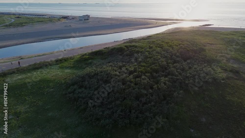 Beautiful flight in summer over the beach in Katwijk aan Zee. People are resting near the sea. Houses for tourists. Beach umbrellas, rides, people swimming in the sea. Beach in Netherland. North Sea. photo