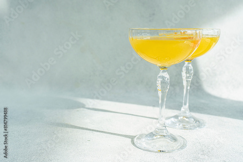 Glass of mimosa cocktail on stone background in sunny day