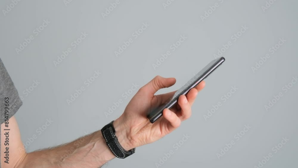 Close-up of a man holding a smartphone in his hand on a black background. Close-up of a man holding a smartphone in his hand on a black background.