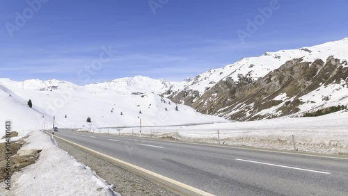 Passing traffic betweeen snowy slopes on Julier Pass in Switzerland on a sunny day - Time Lapse photo