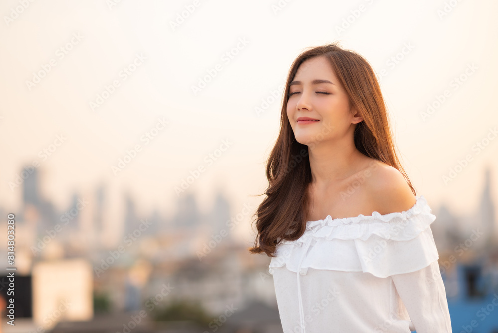 Portrait of Happy young Asian woman with eyes closed smiling in the city background outdoor. Portrait of Happy young Asian woman with eyes closed smiling in the city background outdoor.